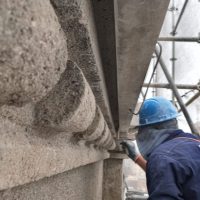Trabajador operario areglando el simil piedra de la fachada de otto wulff